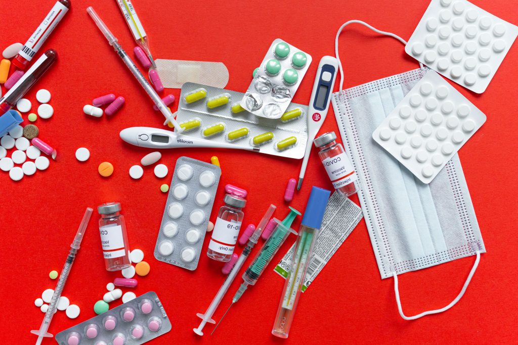 Medical supplies and medications displayed on a red background, emphasizing healthcare essentials.